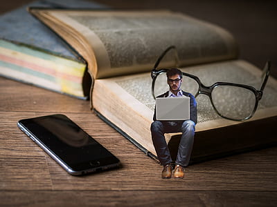 man with laptop edited photo sitting on book with eyeglasses near black iPhone 7 thumbnail