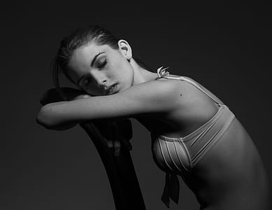 grayscale photo of woman wearing bra leaning thumbnail