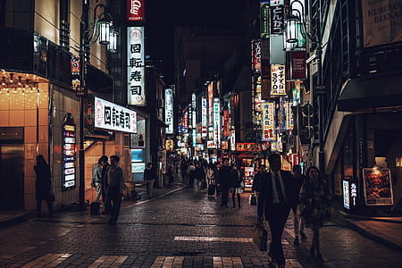 photo of person walking on roadway between buildings during nighttime thumbnail