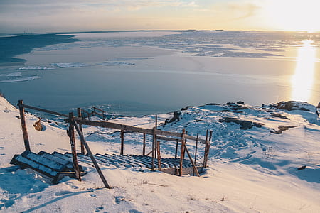 brown wooden dock near body of water covered by snow thumbnail
