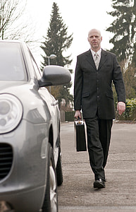 photo of man wearing black notch lapel suit, dress pants and dress shoes and holding brief case thumbnail