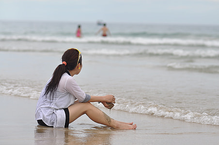 woman wearing white shirt sitting on seashore thumbnail