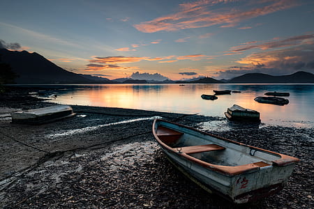 brown and white boat on lake side during sunset thumbnail