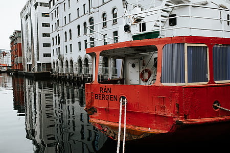 red and white boat on body of water beside white high-rise building thumbnail