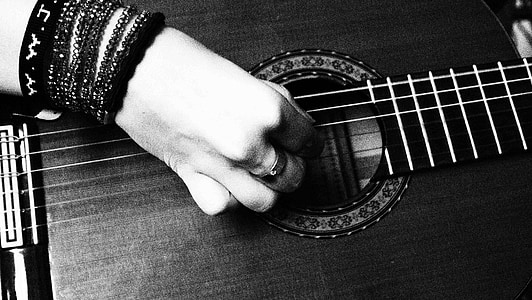 black and gray photo of hand playing guitar thumbnail