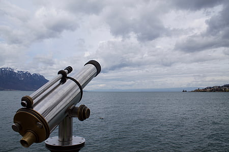 close-up photography of telescope near body of water under white clouds thumbnail