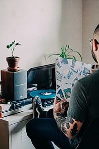man holding book beside wooden cabinet thumbnail