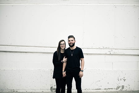 woman standing beside man beside white wall thumbnail