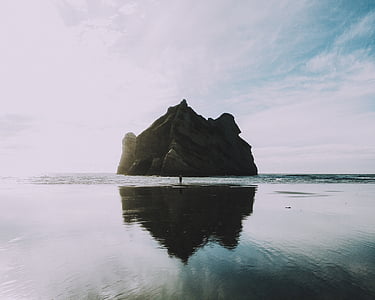 person standing on body of water near rock formation thumbnail