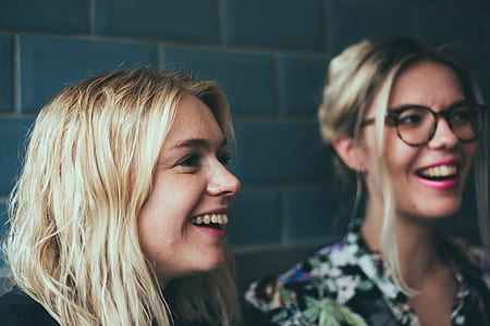 two women smiling leaning against blue wall thumbnail