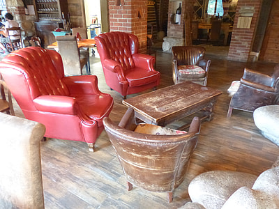 rectangular brown wooden center table beside two red quilted leather wing chairs thumbnail