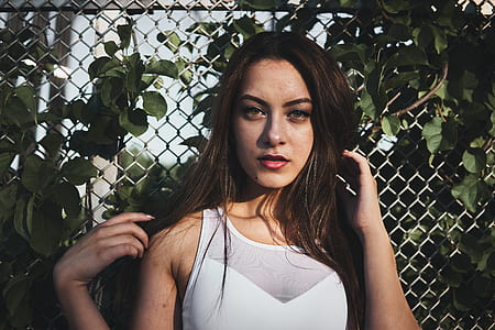 Woman in White Tank Top Standing Near Gray Metal Wire Fence thumbnail