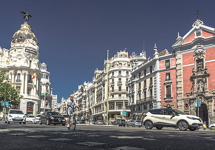 man riding bike near vehicle and buildings during daytim thumbnail