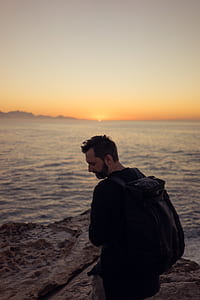 man carrying backpack on mountain cliff thumbnail