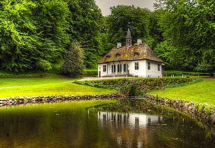 brown and white concrete house near body of water thumbnail