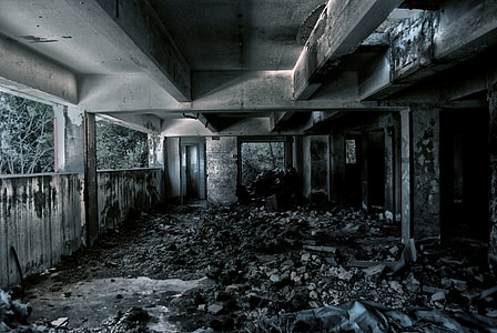 abandoned concrete building surrounded with dirt, rocks and trees during daytime thumbnail
