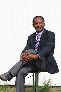 smiling man in suit sitting on swivel chair thumbnail