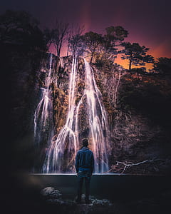 man staring at flowing waterfall at daytime thumbnail