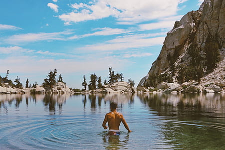 man on body of water under blue sky thumbnail