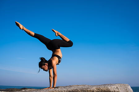 woman standing on hand doing yoga pose on gray surface thumbnail
