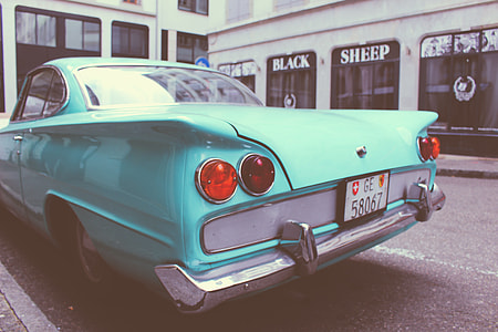 teal coupe parked near white building thumbnail