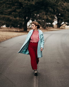 woman in teal coat walking on road thumbnail