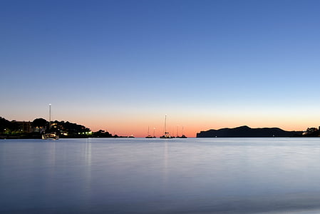silhouette of mountains beside large body of water at golden our thumbnail