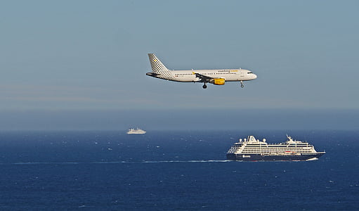 white airliner above ocean near cruise ship thumbnail