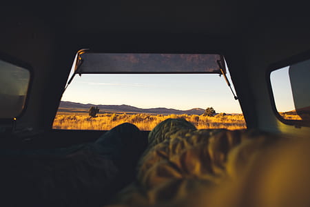 person lying inside tent looking and brown grassfield thumbnail