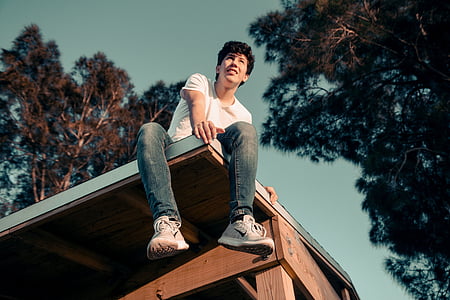 low angle photo of man sitting on the roof of the house thumbnail