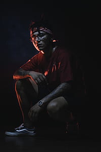 man in red crew-neck shirt sitting with black background thumbnail