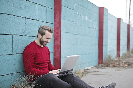 Man Leaning Against Wall Using Laptop thumbnail