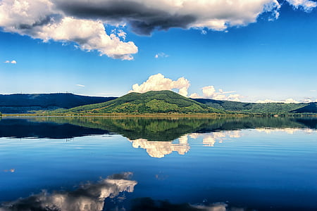 body of water across mountain during daytime thumbnail