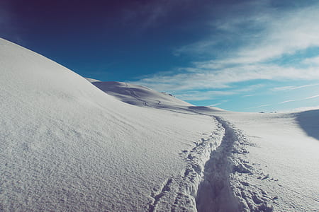 trail left on snow-covered field and hills thumbnail