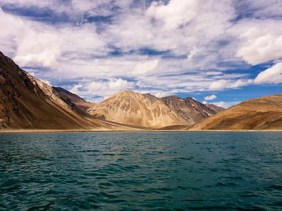 brown mountains near body of water during day time thumbnail