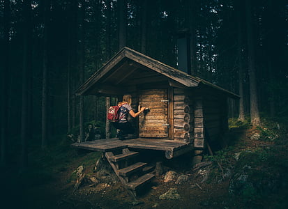 woman kneeling on brown wooden house in the middle of woods thumbnail