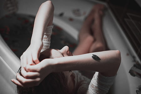 woman sitting on bathtub while raising her hand overhead inside room thumbnail