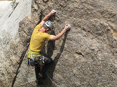 man wearing yellow shirt climbing on rock thumbnail