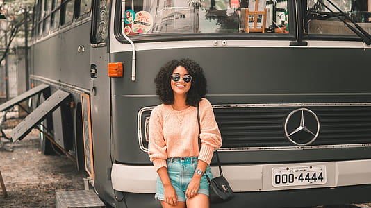 woman smiling while leaning on gray Mercedes-Benz bus at daytime thumbnail