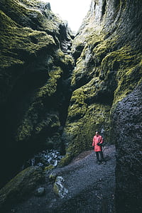 man wearing red coat near stones thumbnail
