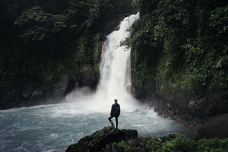 man standing near waterfalls during daytime thumbnail