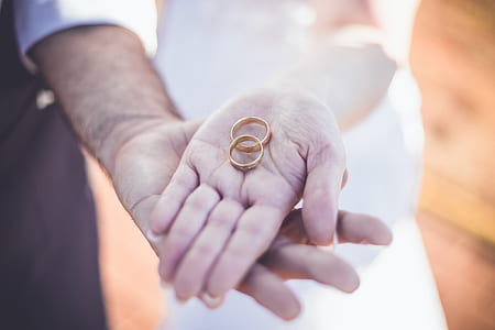 person holding gold-colored wedding bands thumbnail