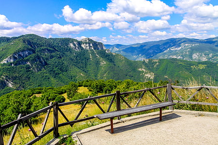 gray bench beside fence on mountain top taken under white clouds during daytime thumbnail