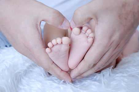 person making hand heart with baby's feet thumbnail