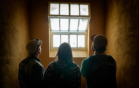 two men and one woman standing near window thumbnail