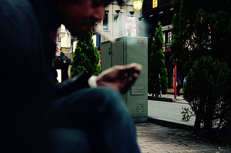 close-up photo of man sitting white lighting a cigarette at daytime thumbnail
