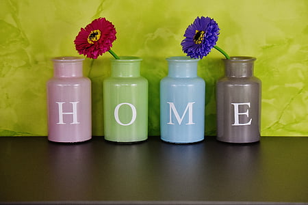 four assorted-color home-printed jars with two flowers on top of wood thumbnail