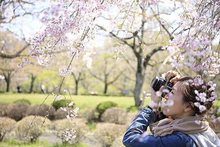 woman taking photo while standing near grass field during daytime thumbnail