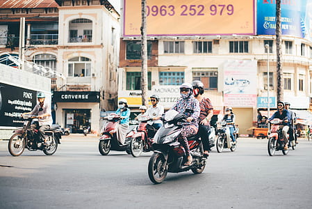 photo of people riding underbone motorcycle near concrete buildings thumbnail