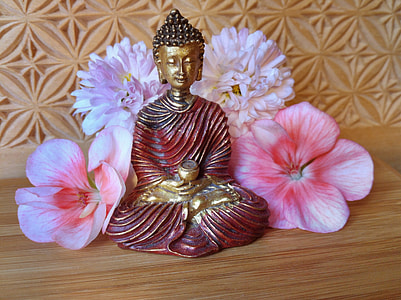 Gautama Buddha figurine surrounded with four pink flowers thumbnail